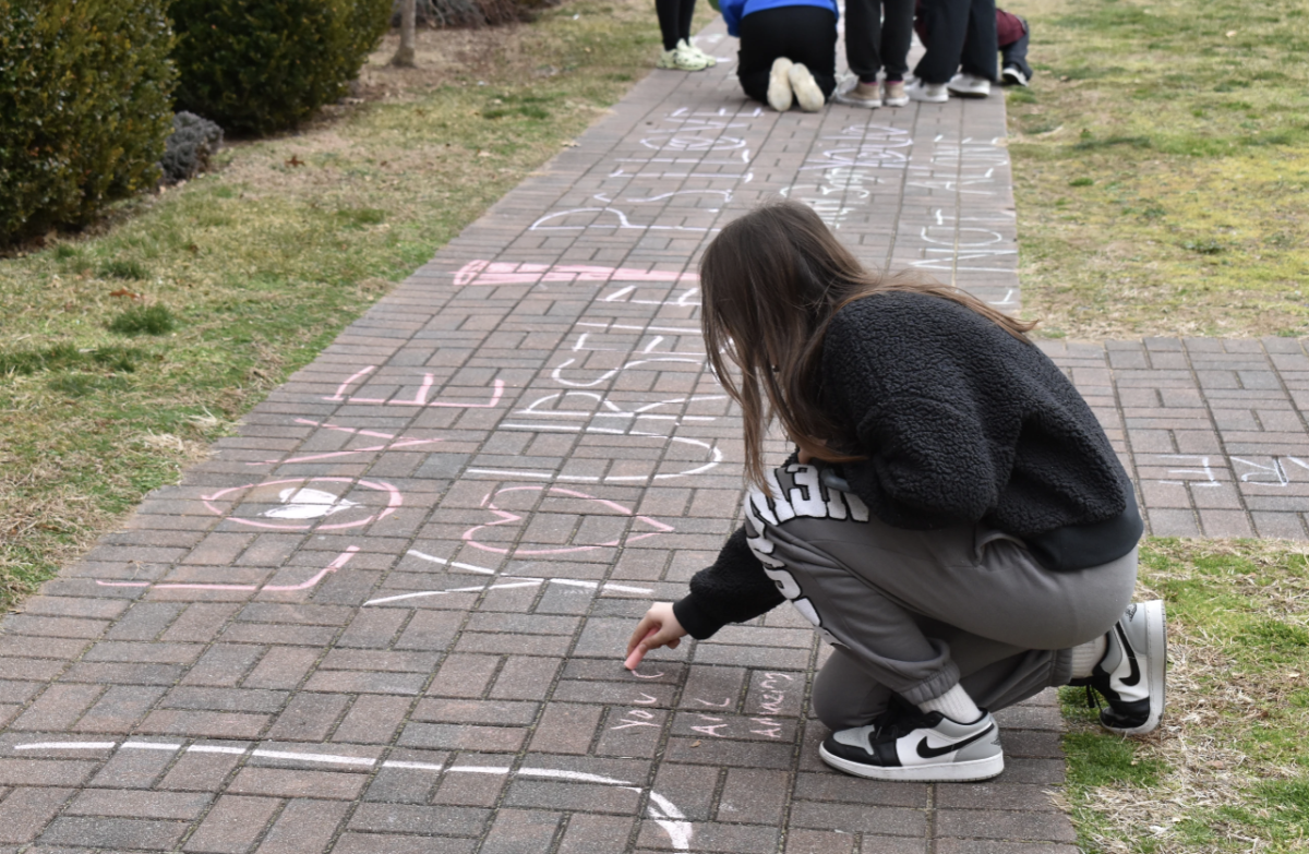 A student contributes to the courtyard artwork, writing encouraging messages for passing staff and students to read.